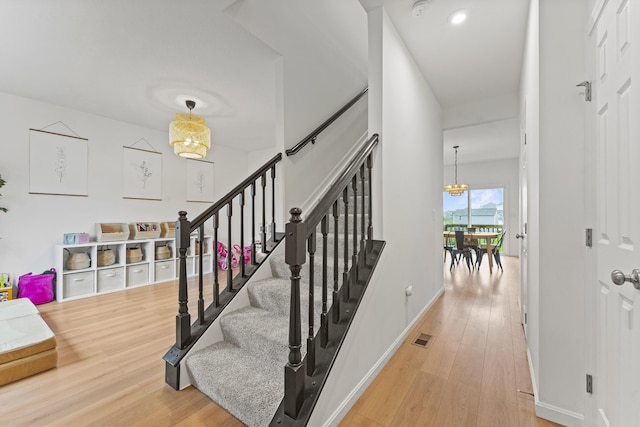 staircase with visible vents, baseboards, wood finished floors, and a chandelier