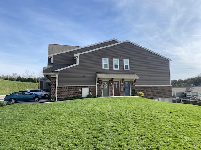 view of front of house with brick siding, roof with shingles, and a front lawn