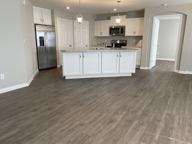kitchen featuring arched walkways, appliances with stainless steel finishes, baseboards, and white cabinetry