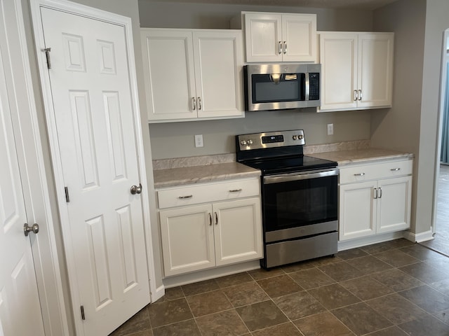 kitchen featuring stainless steel appliances, light countertops, and white cabinetry
