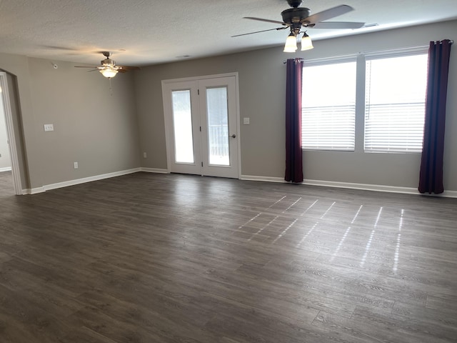 unfurnished living room featuring baseboards, a textured ceiling, ceiling fan, and dark wood finished floors