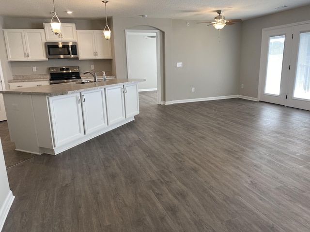 kitchen featuring a ceiling fan, open floor plan, arched walkways, white cabinetry, and appliances with stainless steel finishes