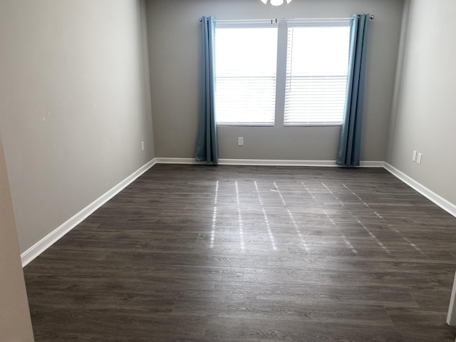 empty room featuring baseboards and dark wood-style flooring