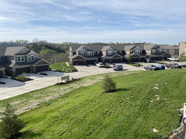 view of yard featuring driveway, a residential view, and a garage