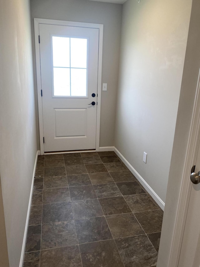 doorway to outside featuring stone finish floor and baseboards