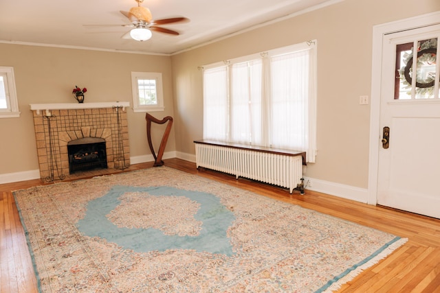 2225 Oakland Ave, Covington, KY 41015 - unfurnished living room featuring radiator heating unit, wood finished floors, a ceiling fan, and ornamental molding