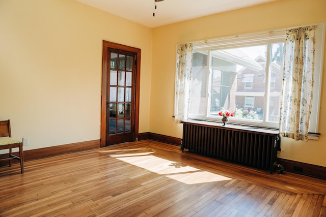 2225 Oakland Ave, Covington, KY 41015 - empty room featuring radiator heating unit, a ceiling fan, baseboards, and light wood-type flooring