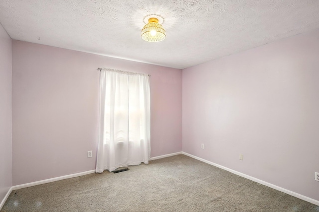carpeted spare room featuring baseboards and a textured ceiling