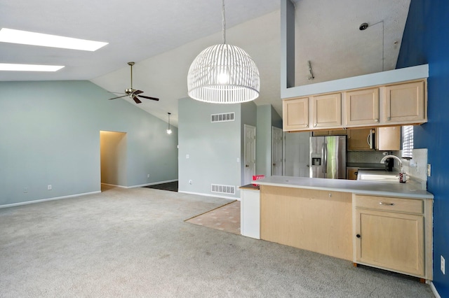 kitchen featuring stainless steel fridge with ice dispenser, light brown cabinetry, a sink, ceiling fan, and high vaulted ceiling