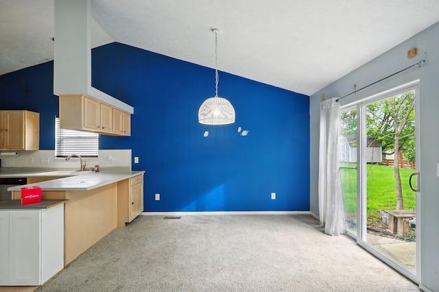 kitchen featuring lofted ceiling, light brown cabinets, light colored carpet, a sink, and hanging light fixtures