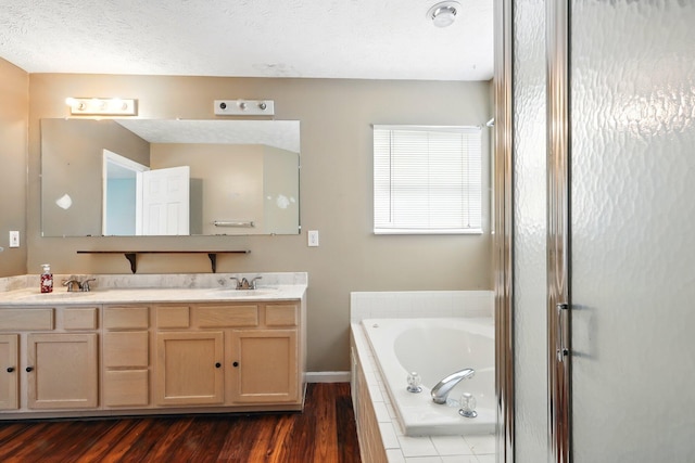 bathroom with a garden tub, wood finished floors, double vanity, and baseboards