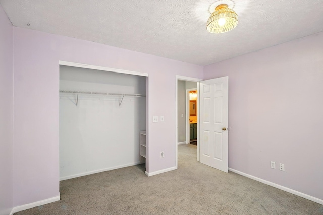unfurnished bedroom featuring carpet, baseboards, a textured ceiling, and a closet