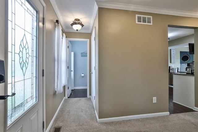 hall featuring visible vents, crown molding, baseboards, and dark carpet