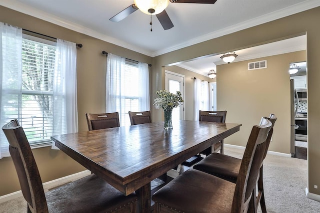 carpeted dining area featuring baseboards, ceiling fan, ornamental molding, and visible vents