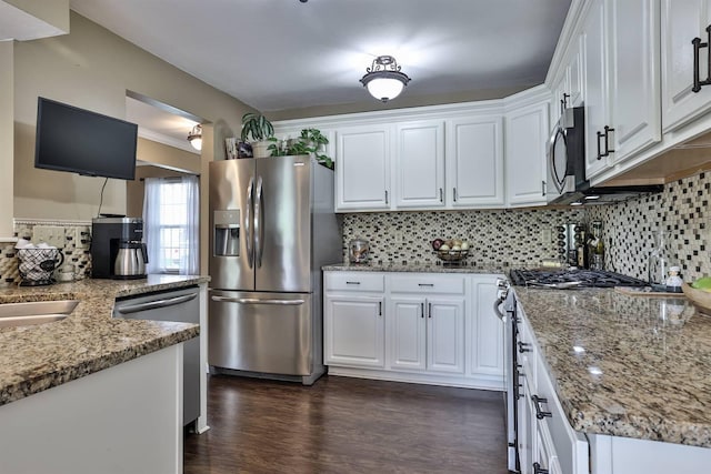 kitchen with light stone counters, decorative backsplash, stainless steel appliances, and white cabinetry
