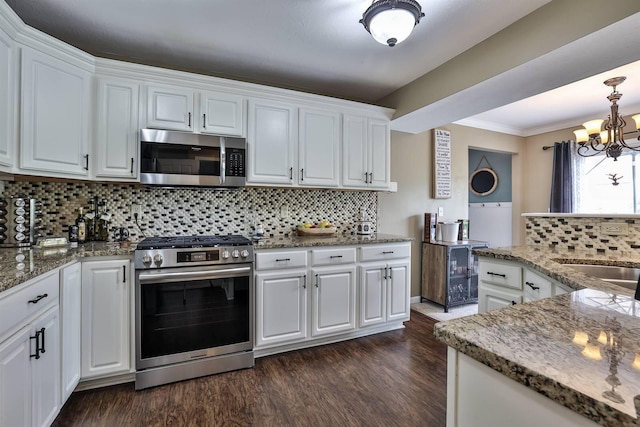 kitchen with decorative backsplash, appliances with stainless steel finishes, dark wood-style floors, a notable chandelier, and white cabinetry