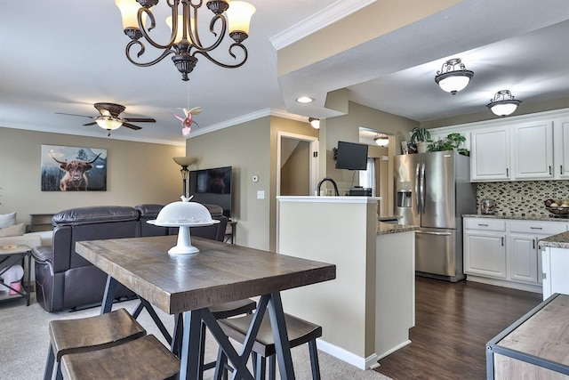 dining room with baseboards, ornamental molding, and ceiling fan with notable chandelier