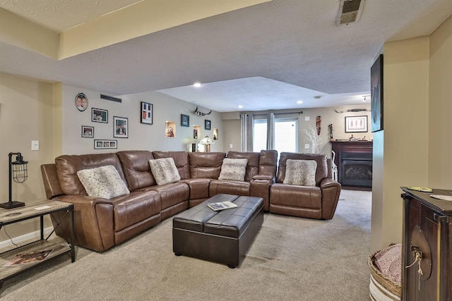living room featuring carpet flooring, a textured ceiling, visible vents, and a fireplace