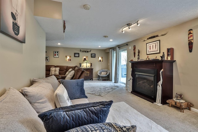 living room featuring a textured ceiling, baseboards, a glass covered fireplace, carpet, and recessed lighting