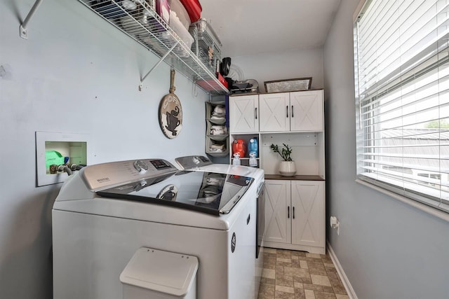 laundry room featuring cabinet space, stone finish flooring, and washer and clothes dryer