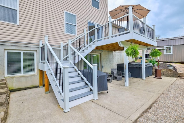 view of patio / terrace with a hot tub, a wooden deck, and stairway