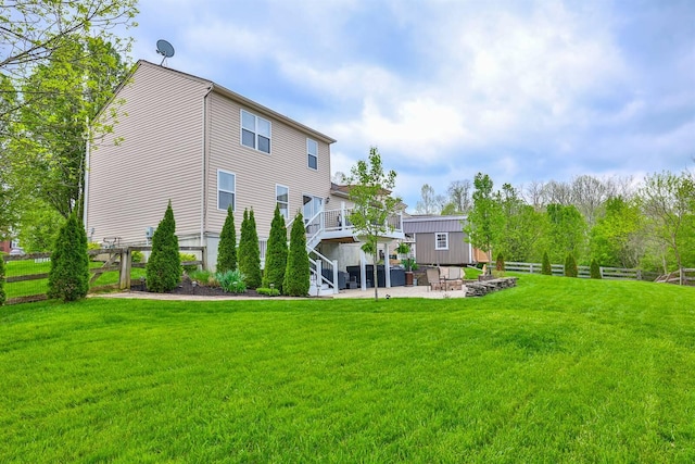 rear view of house with fence, a wooden deck, stairway, a patio, and a yard