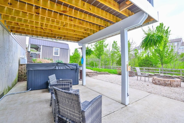 view of patio featuring a fenced backyard, a hot tub, and an outdoor fire pit
