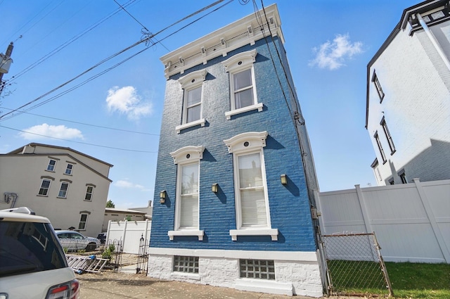 italianate-style house with brick siding and fence