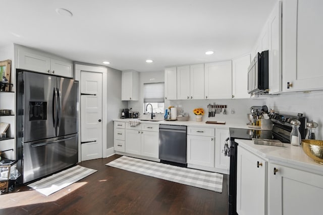 kitchen with dark wood finished floors, white cabinetry, stainless steel appliances, and a sink