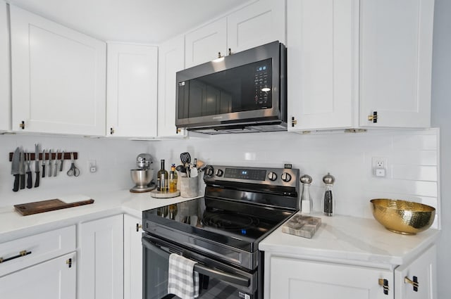 kitchen with stainless steel microwave, backsplash, white cabinets, and black electric range oven