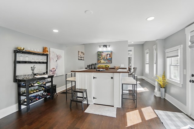bar featuring recessed lighting, baseboards, dark wood-style floors, and bar area