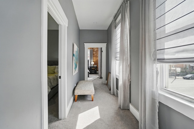 hall with baseboards and light colored carpet