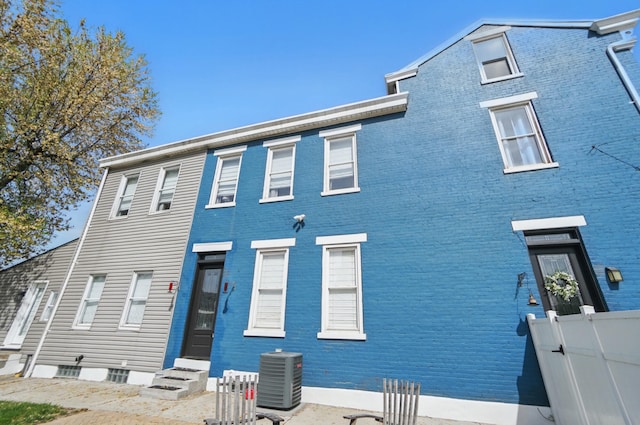 view of front of home with brick siding, fence, cooling unit, and entry steps