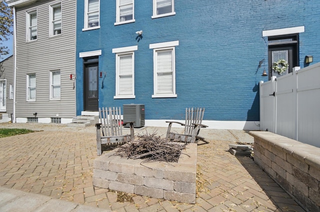 rear view of property featuring central AC, brick siding, and fence