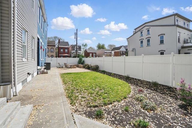 view of yard with a residential view, central air condition unit, a patio, and a fenced backyard