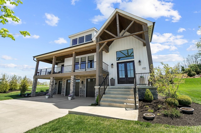 view of front of house featuring a front lawn, a balcony, concrete driveway, french doors, and a garage