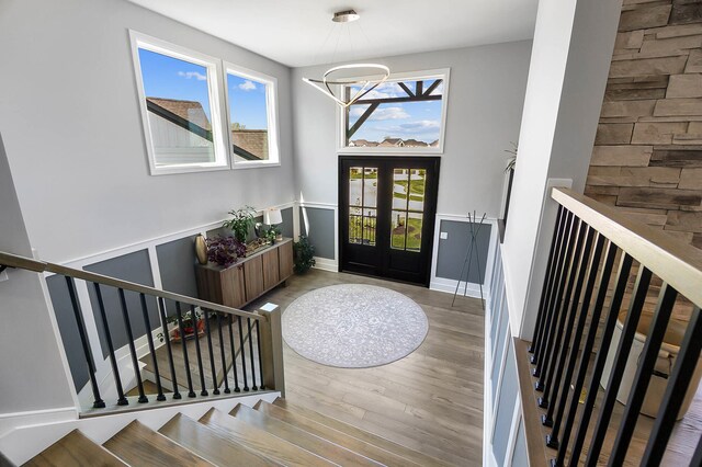 entrance foyer with stairway, wood finished floors, french doors, baseboards, and a notable chandelier