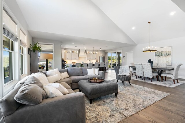 living area with recessed lighting, wood finished floors, high vaulted ceiling, and a notable chandelier