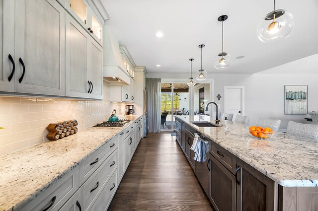 kitchen featuring backsplash, glass insert cabinets, light stone countertops, and a sink