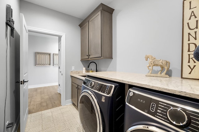 washroom featuring separate washer and dryer, baseboards, cabinet space, and a sink