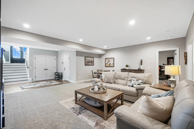 living room featuring light colored carpet, baseboards, stairs, and recessed lighting