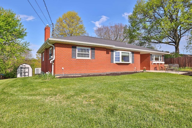 ranch-style home with fence, brick siding, a front yard, a chimney, and a patio