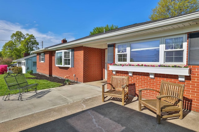 exterior space featuring brick siding and a patio