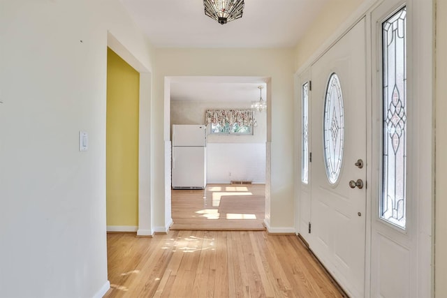 entrance foyer featuring baseboards, light wood-style flooring, visible vents, and an inviting chandelier