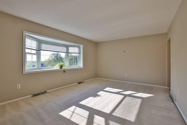empty room featuring baseboards, visible vents, and carpet