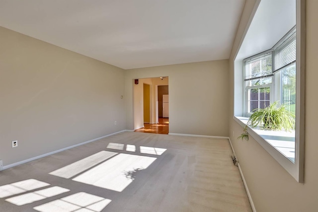 unfurnished room with baseboards and light carpet