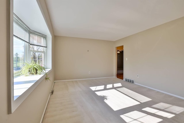 empty room with baseboards, visible vents, and light colored carpet