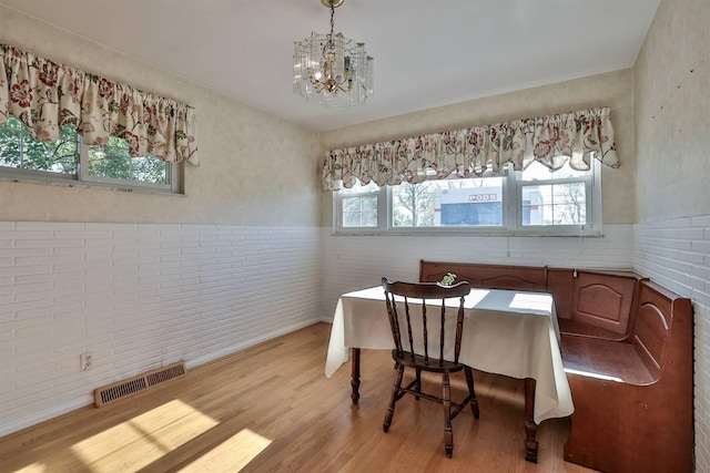 dining room featuring visible vents, light wood finished floors, wainscoting, and an inviting chandelier