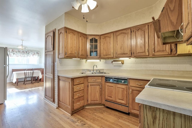 kitchen featuring a sink, dishwasher, brown cabinets, and range hood