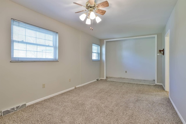 unfurnished room with visible vents, carpet flooring, baseboards, and a ceiling fan